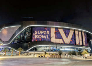 Exterior shot of a football stadium at night in Las Vegas, with an enormous sign reading "Super Bowl LVIII"