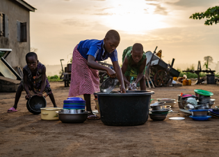 Two girls and their little brother in Lome, Togo, work hard to prepare for the day. Credit: Jordan Rowland, Unsplash