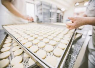 A cookie sheet covered in rows of cookie dough in an industrial kitchen.