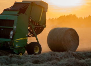 A hay baler with a freshly rolled bale. Photo by Jed Owen on Unsplash